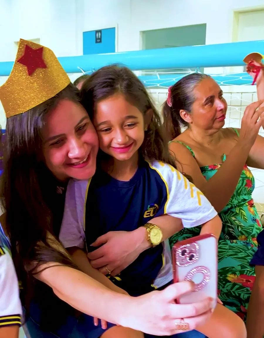 Mãe e filha sorrindo juntas em uma festa na escola